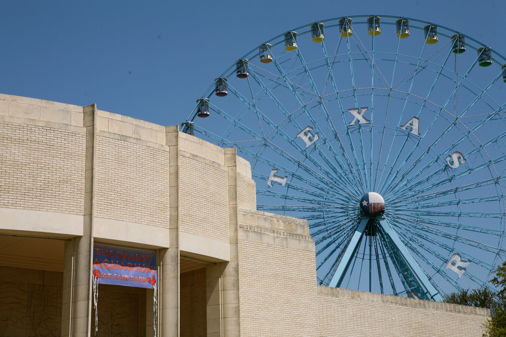 A view of the Ferris wheel behind the top corner of the neighborhood aquarium at Fair Park near The Element apartments in Dallas Texas