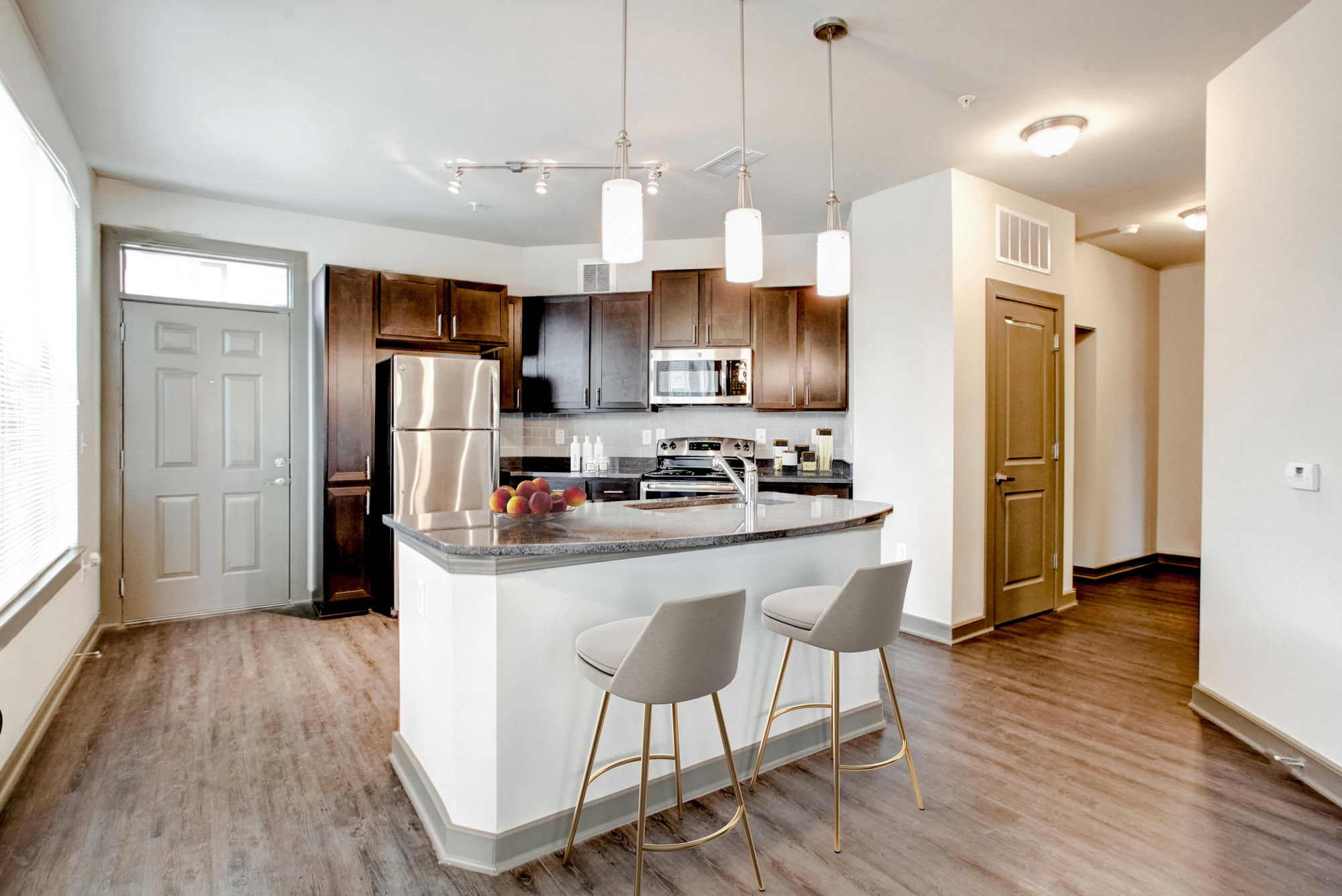 Two bar stools sit against a kitchen island with a full-equipped kitchen in the background.