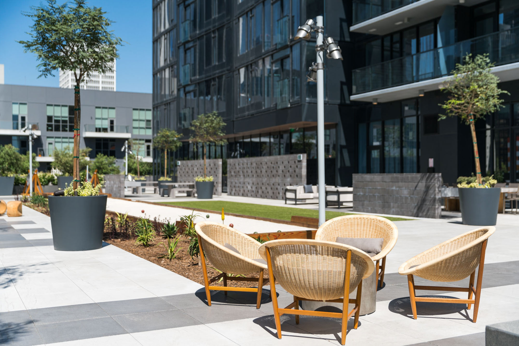A courtyard with ourdoor seating, lights and views of the Atelier high rise apartments in downtown Los Angeles