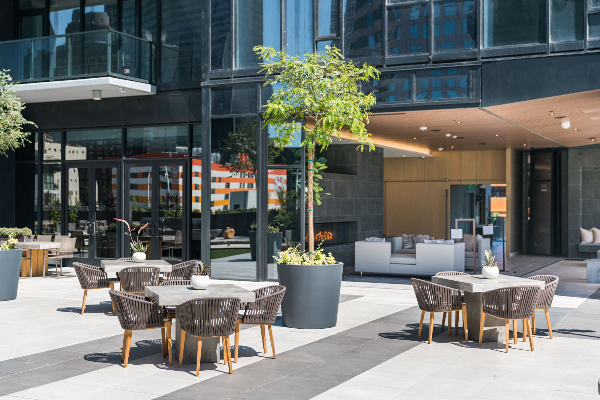 A courtyard with several tables for seating and dining, lounging areas and large dining tables at Ateliers luxury apartments in downtown LA