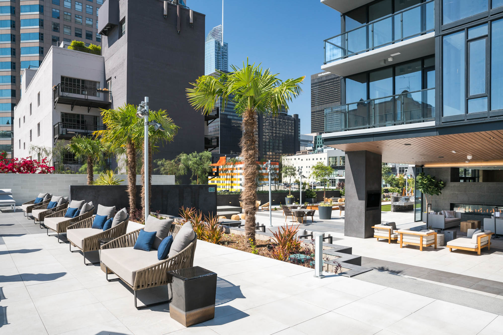A courtyard with rows of outdoor bench chairs, group lounging spaces under apartment balconies at Ateliers luxury apartments in downtown LA
