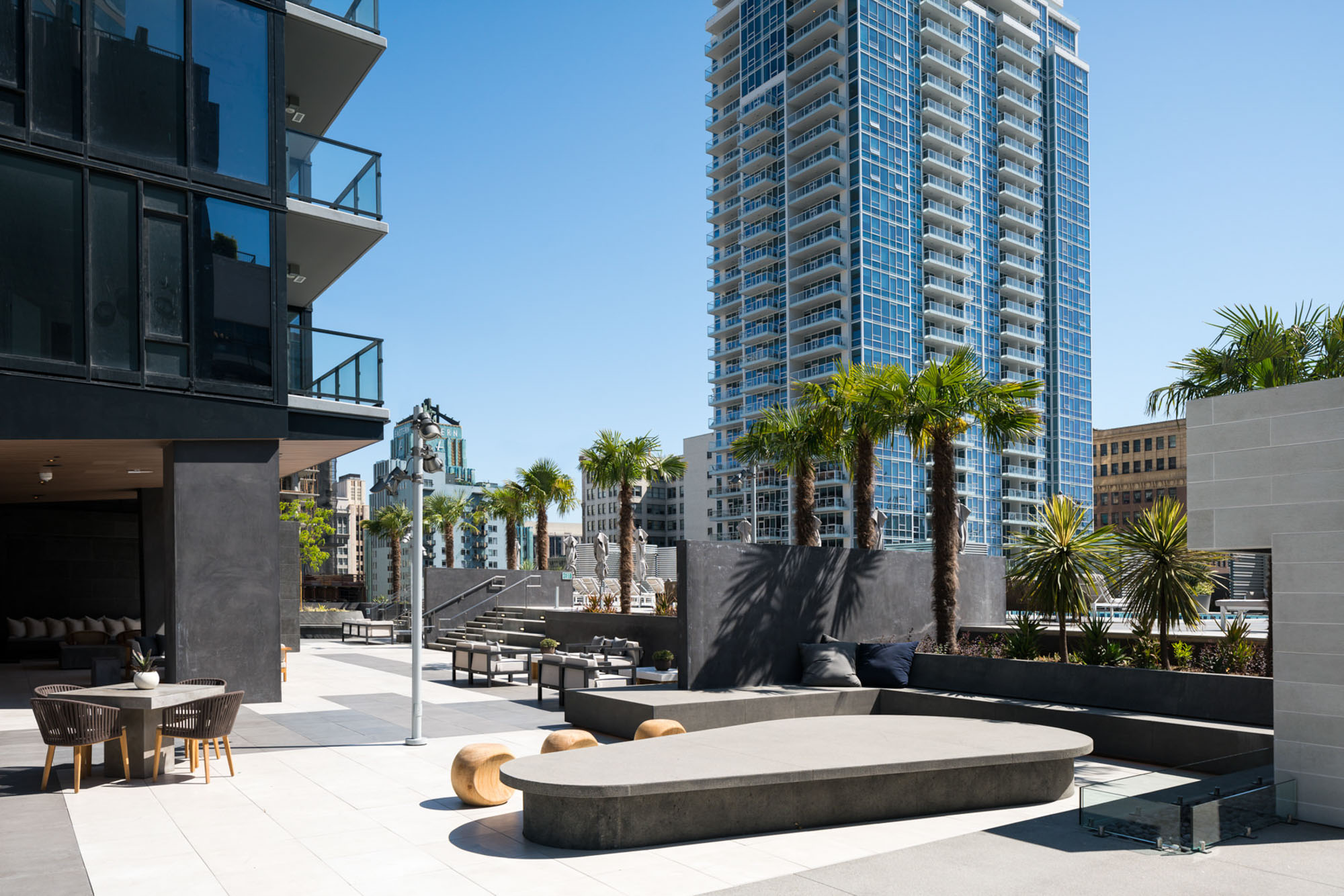 A modern courtyard with sleek benches and tables with views of surrounding skyscrapers at Ateliers in downtown Los Angeles