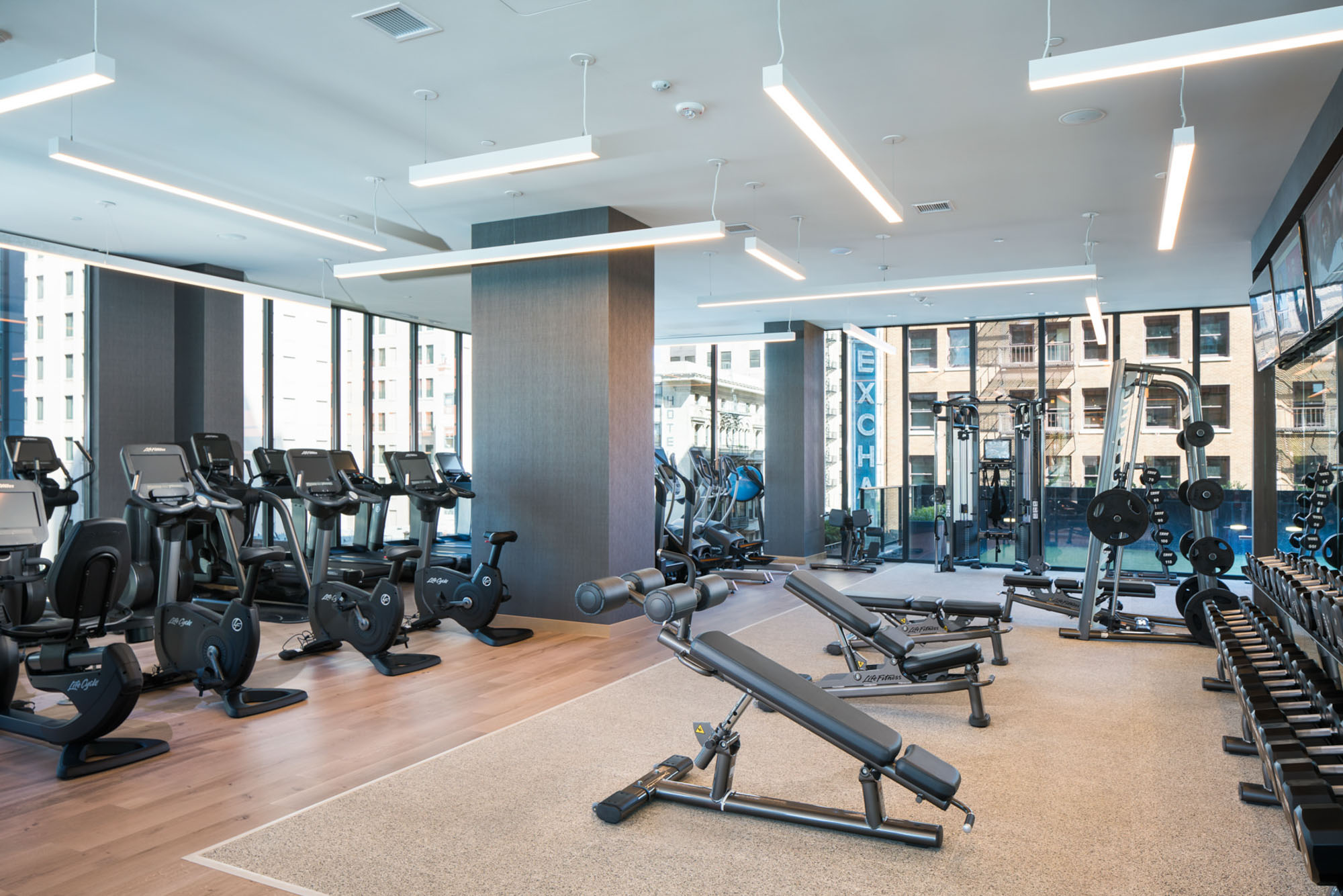 A fully equipped fitness center with weights, machines and glass walls with city views at Ateliers luxury apartments in downtown los angeles