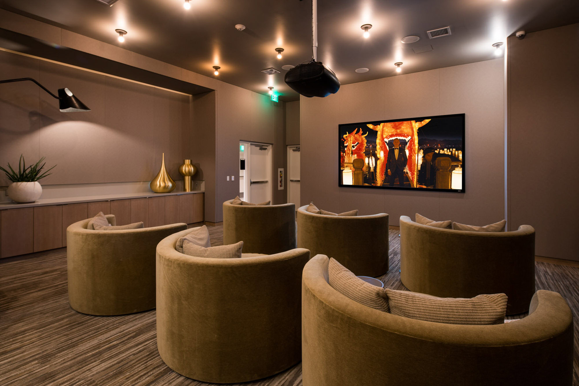 A modern, elegant media lounge with comfortable chairs, and dim lighting at Ateliers downtown la apartments