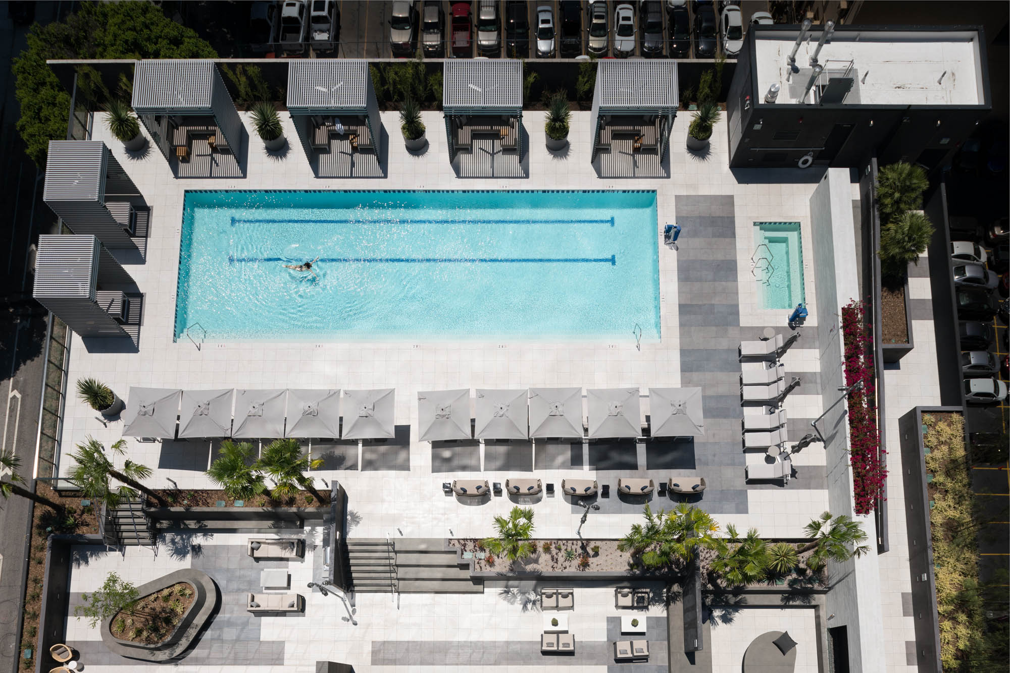 The rooftop terrace with outdoor seating area, a pool, lounging chairs canaba's and umbrella's at Atelier apartments downtown Los Angeles