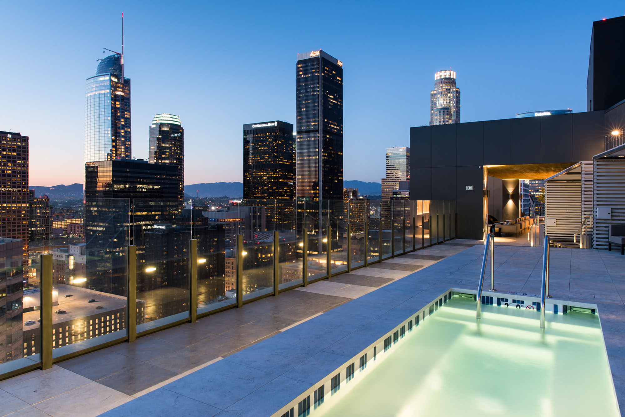 A rooftop pool with a view of the city skyline taken at twilight with lights shining at Atelier apartments in downtown Los Angeles
