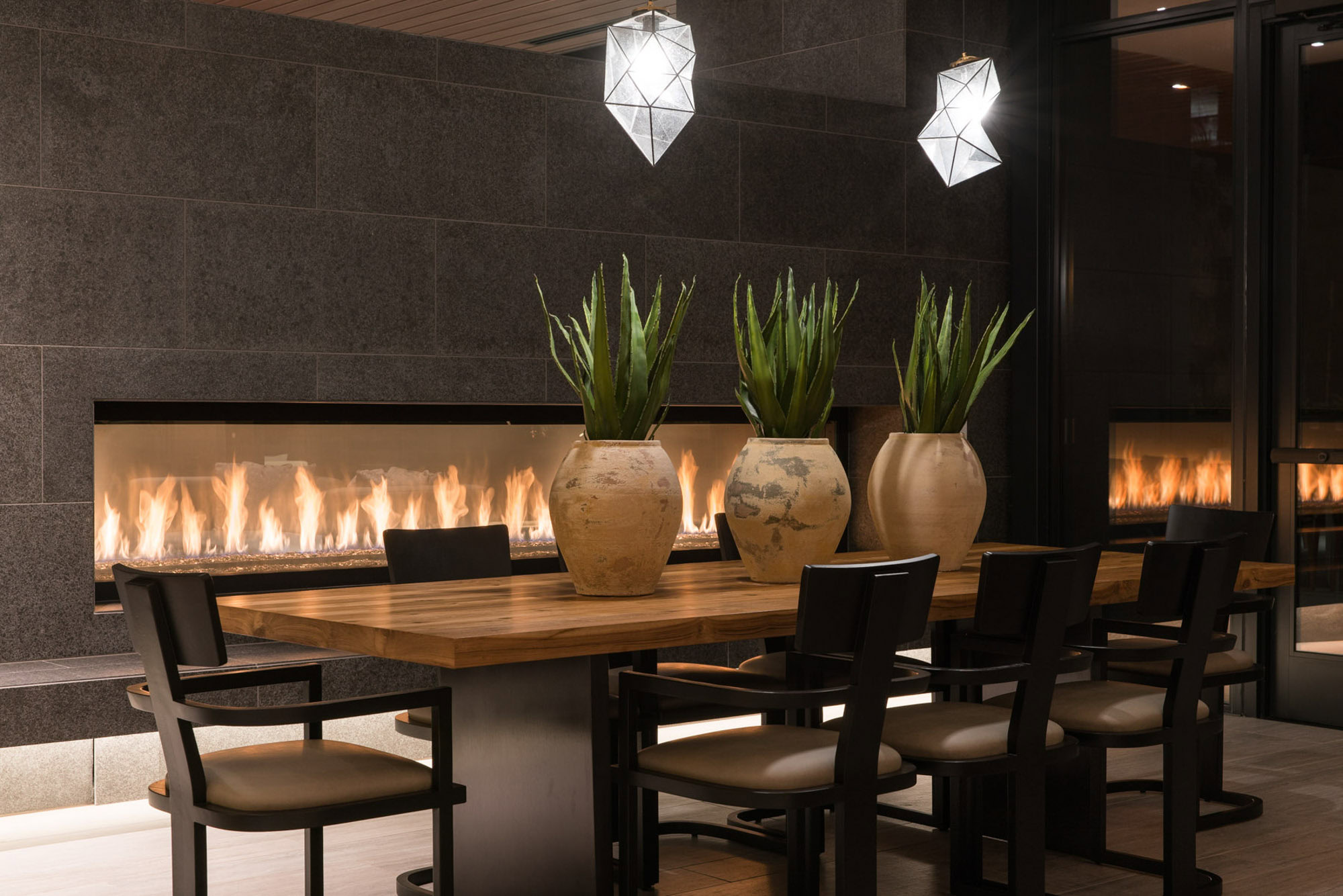 A modern dining room space with with a dining table, and a modern fireplace at Ateliers DTLA luxury apartments