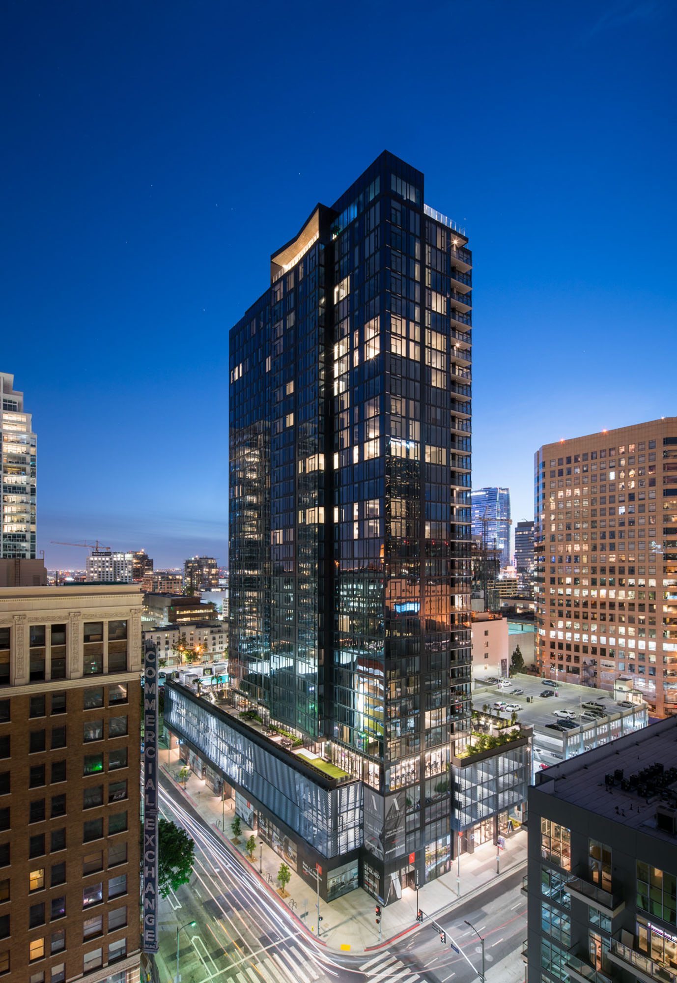 The exterior of Ateliers luxury apartments in downtown LA in the evening with the bright city lights of downtown LA