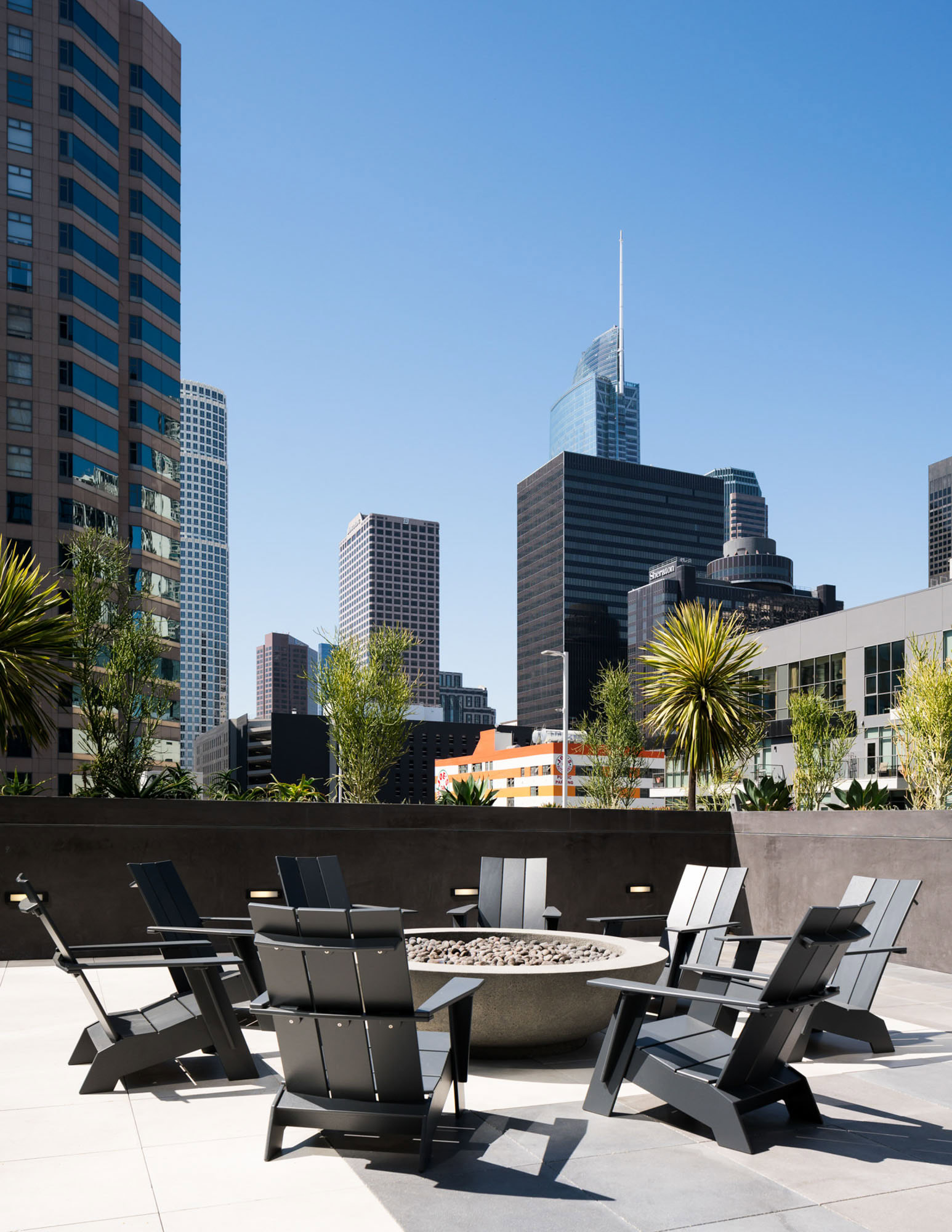 A rooftop terrace with lounging chairs surrounding a firepit at Ateliers luxury apartments in downtown LA