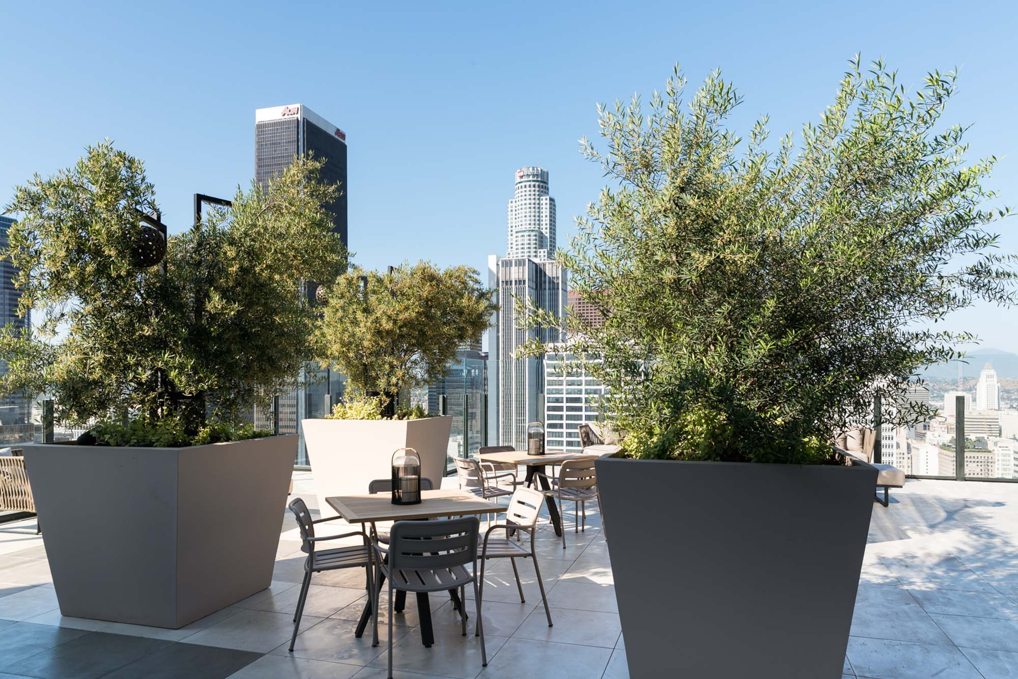A rooftop terrace with lounging chairs and a view of the city skyline at Ateliers luxury apartments in downtown LA