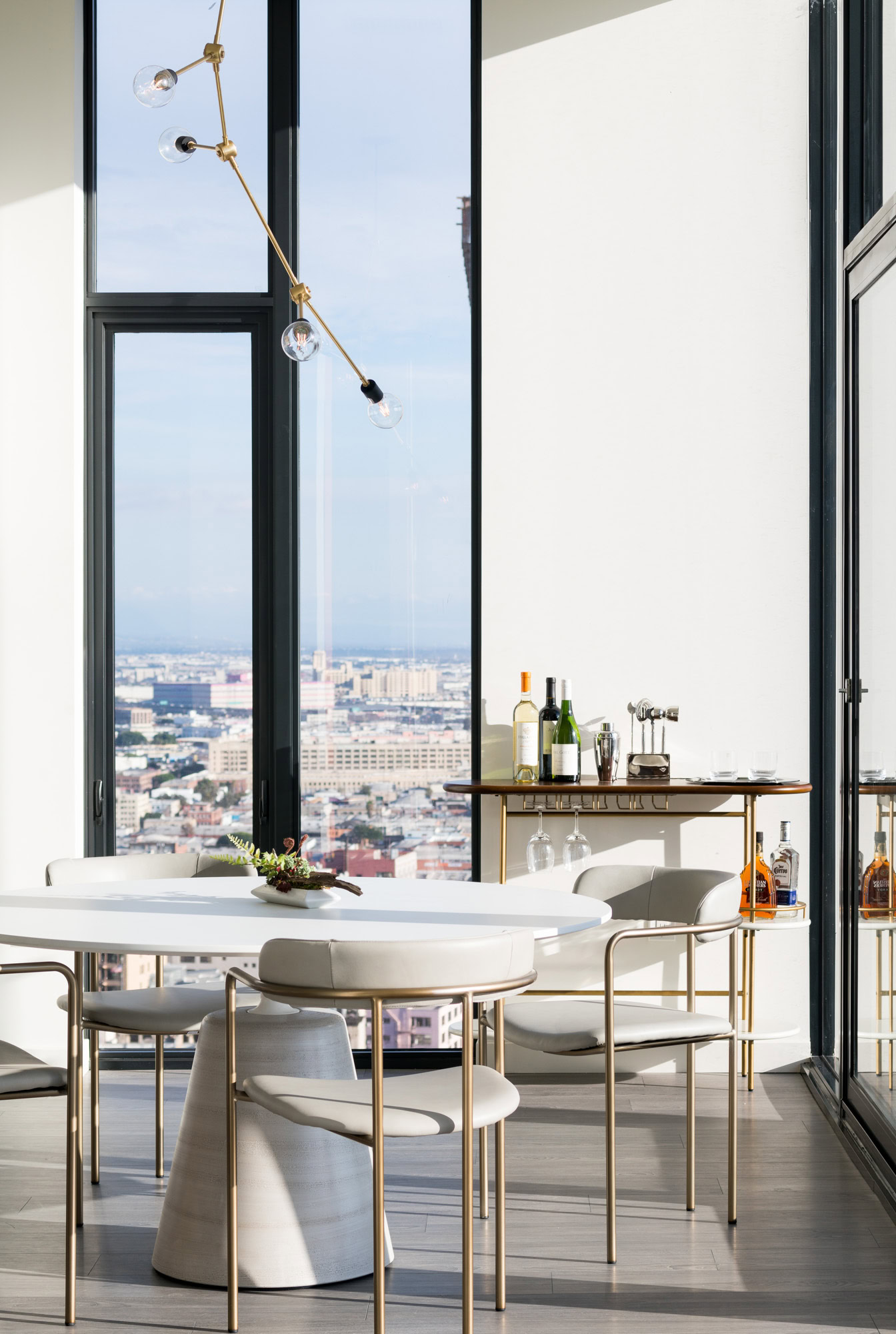 A dining area brightly lit by floor to ceiling windows at Ateliers luxury apartments in dowtown LA