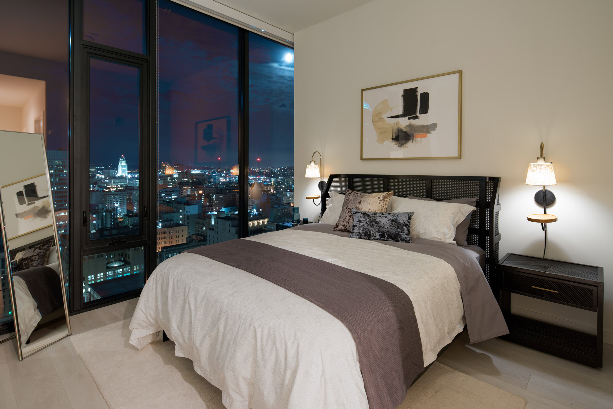 A bedroom with floor to ceiling windows showing city views at Atelier apartments in downtown Los Angeles