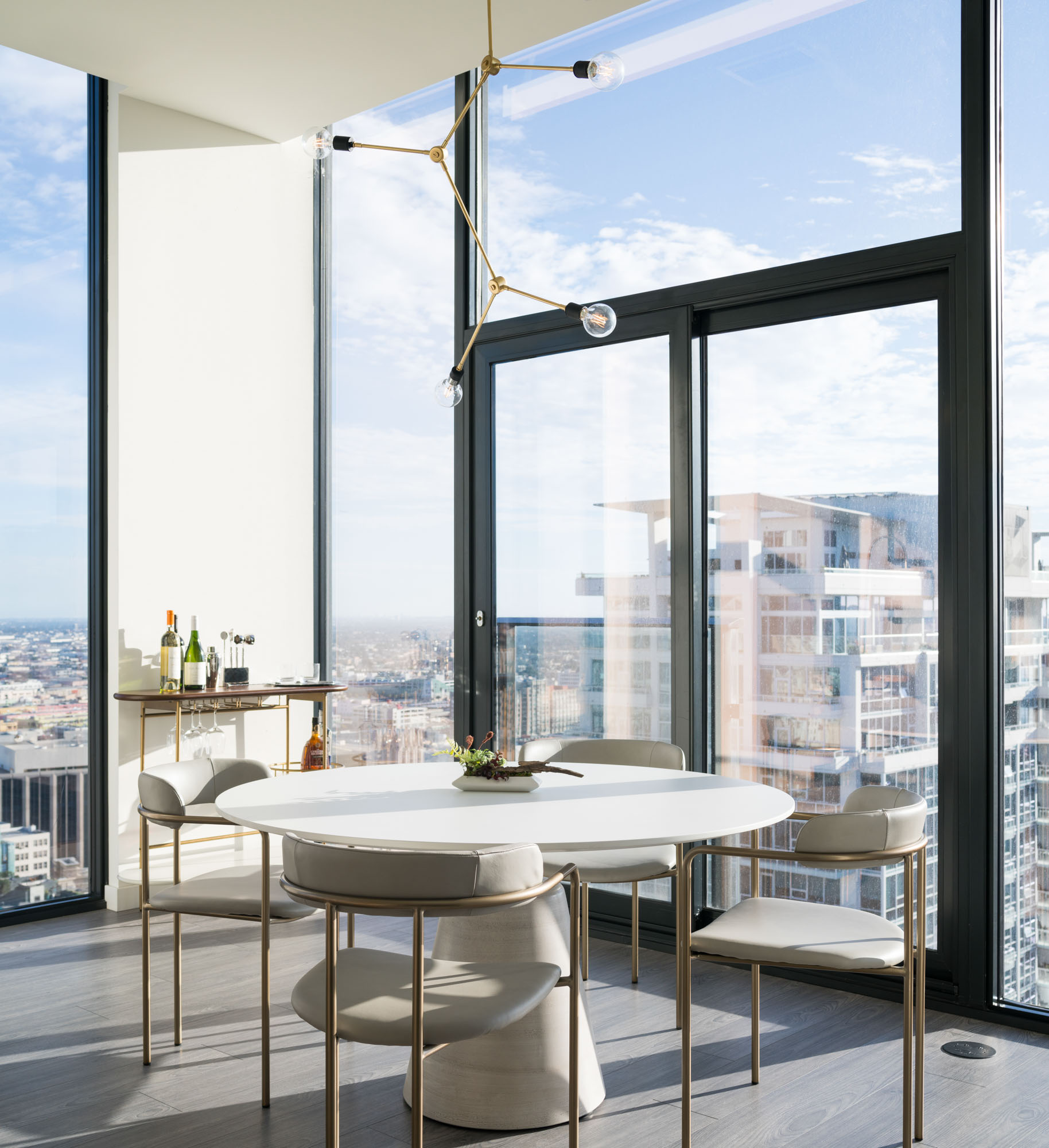 A dining area in front of floor to ceiling walls and doors leading to a balcony area at Ateliers high rise apartments in downtown LA