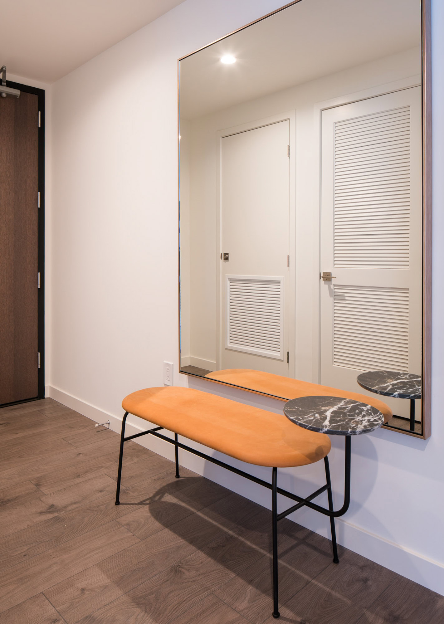 An entry foyer with a large mirror and a bench at an Atelier apartment in downtown LA