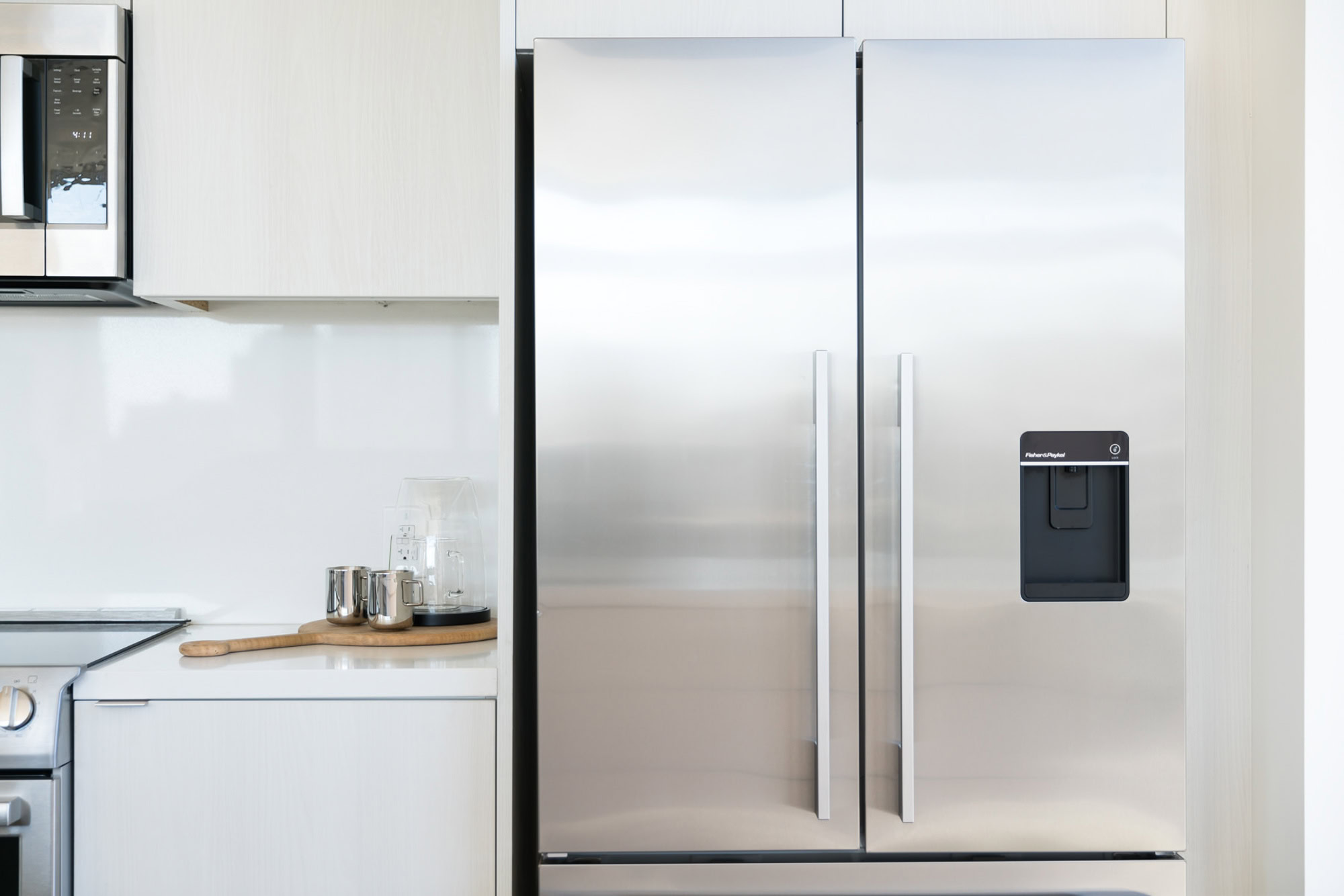 A stainless steel fridge in an elevated kitchen with glacier white quartz backsplashes and countertops at Ateliers luxury apartments in downtown LA