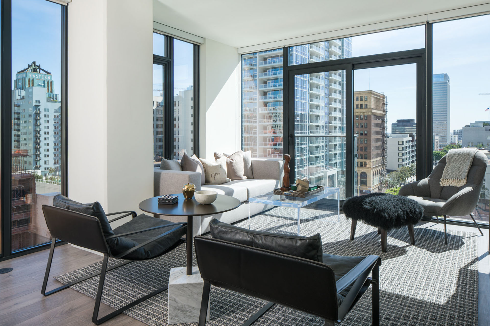 A living room area surrounded by floor to ceiling window walls showing city views