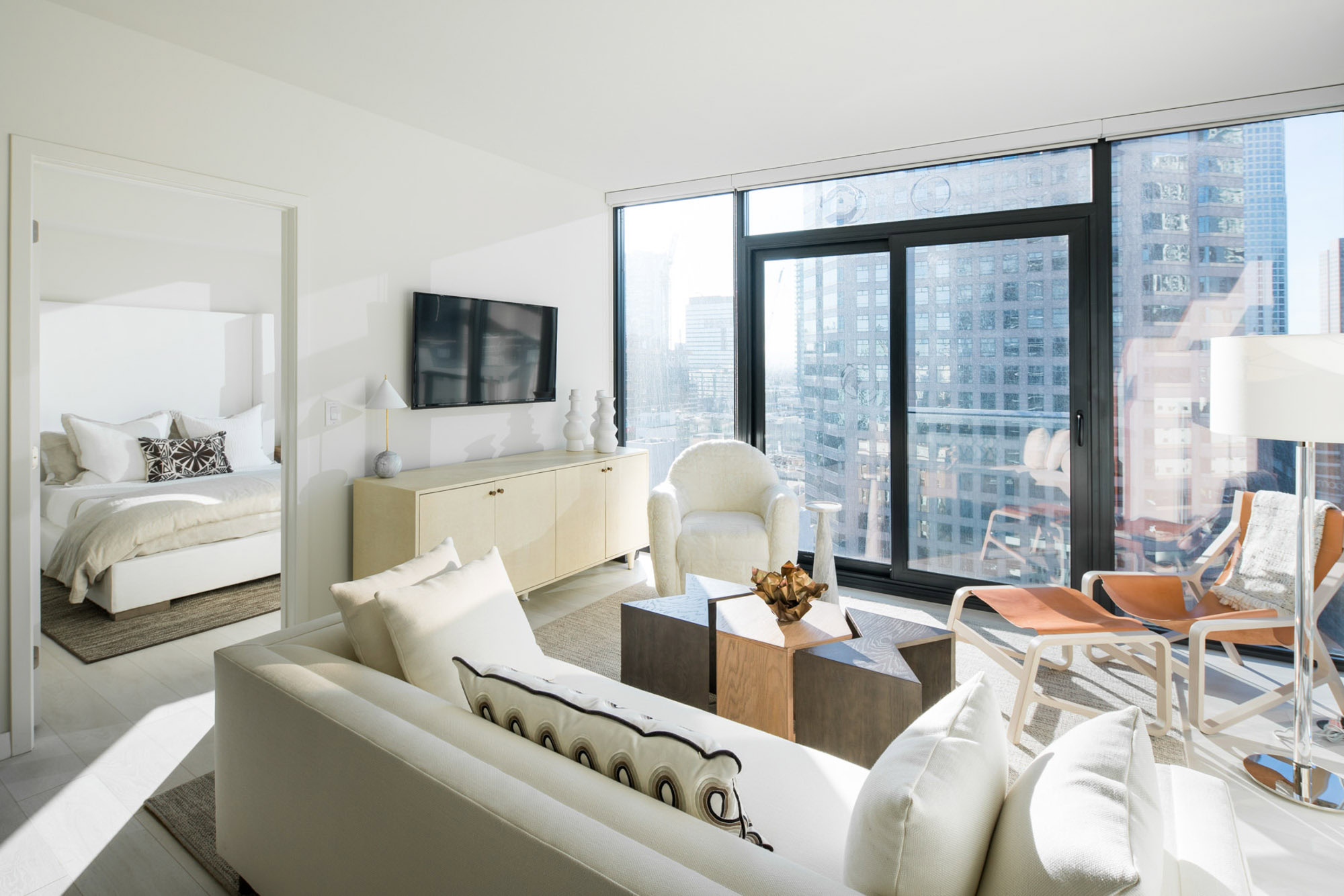 A living room with a glass wall and a door leading to a bedroom at Ateliers luxury apartments in downtown LA
