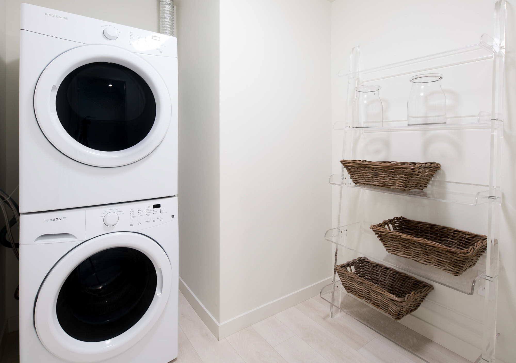 A spacious laundry room with a stacked washer and dryer, and mounted storage space in an Atelier apartment in downtown LA