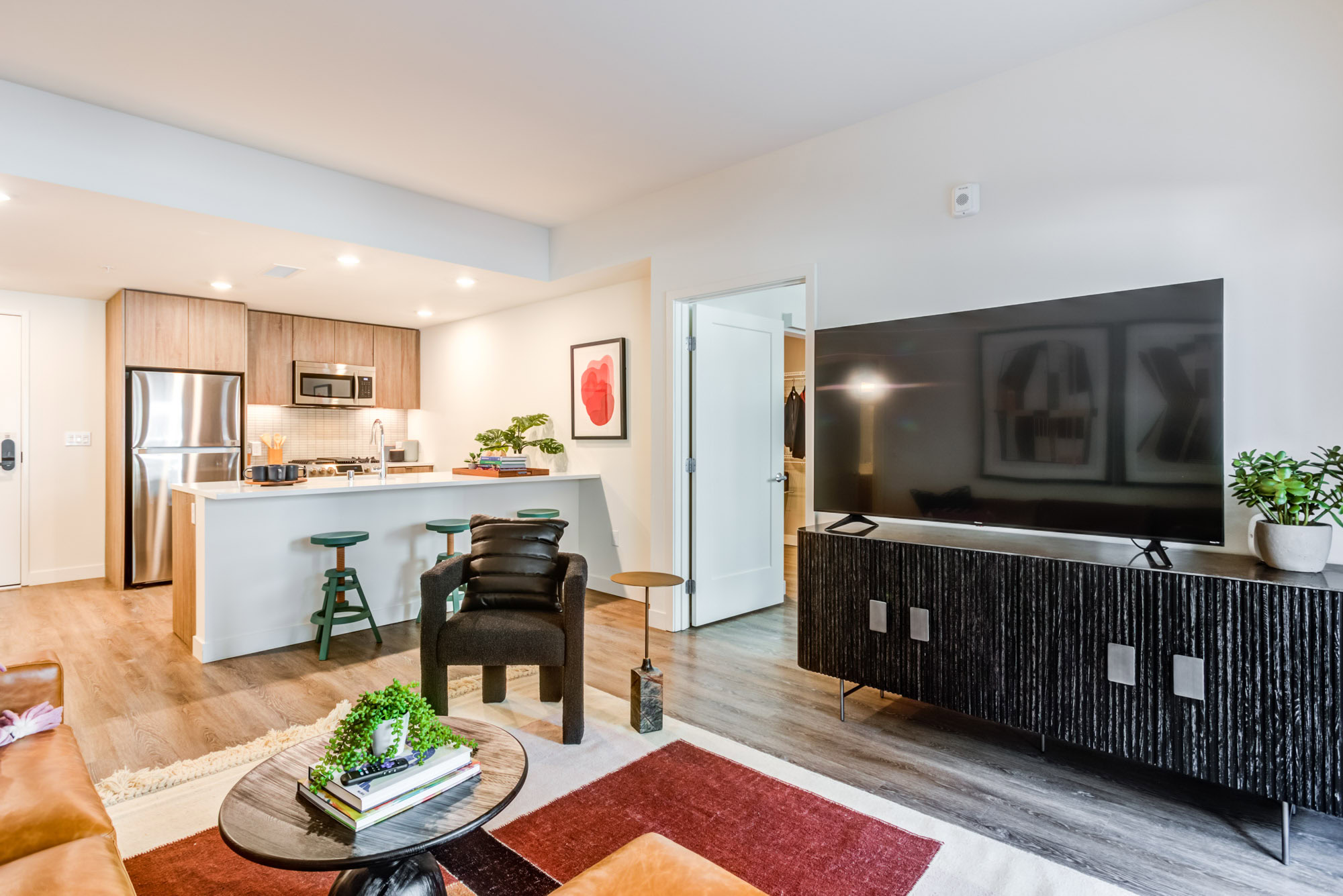 A living room with hardwood floors and kitchen with a peninsula at the Webster Eleven apartments in downtown Oakland