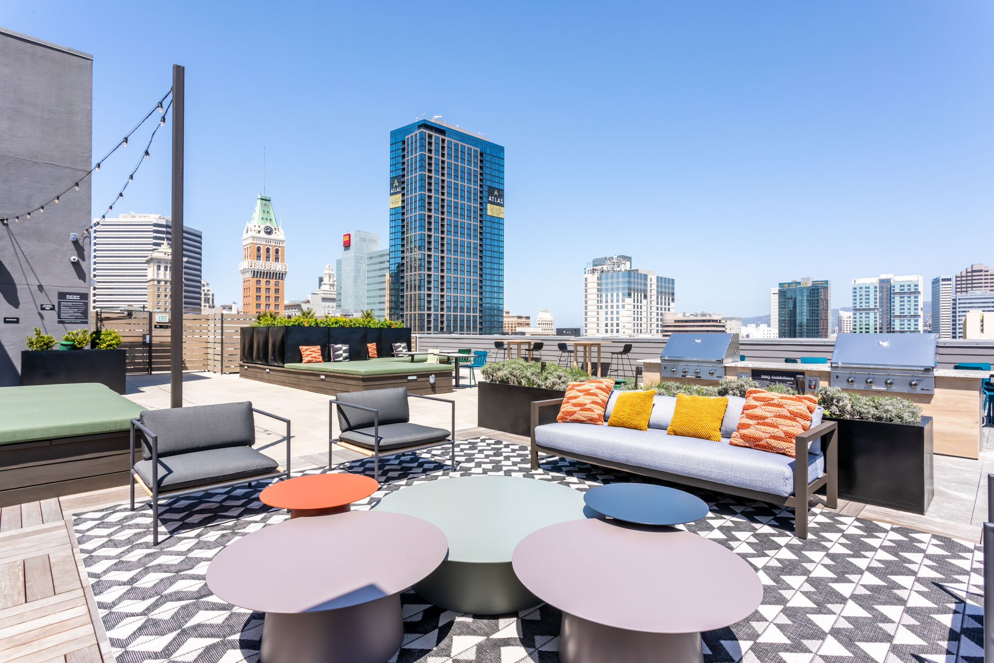 A rooftop lounge with seating and high tables and chairs and 360 views at the Webster Eleven apartments in downtown Oakland