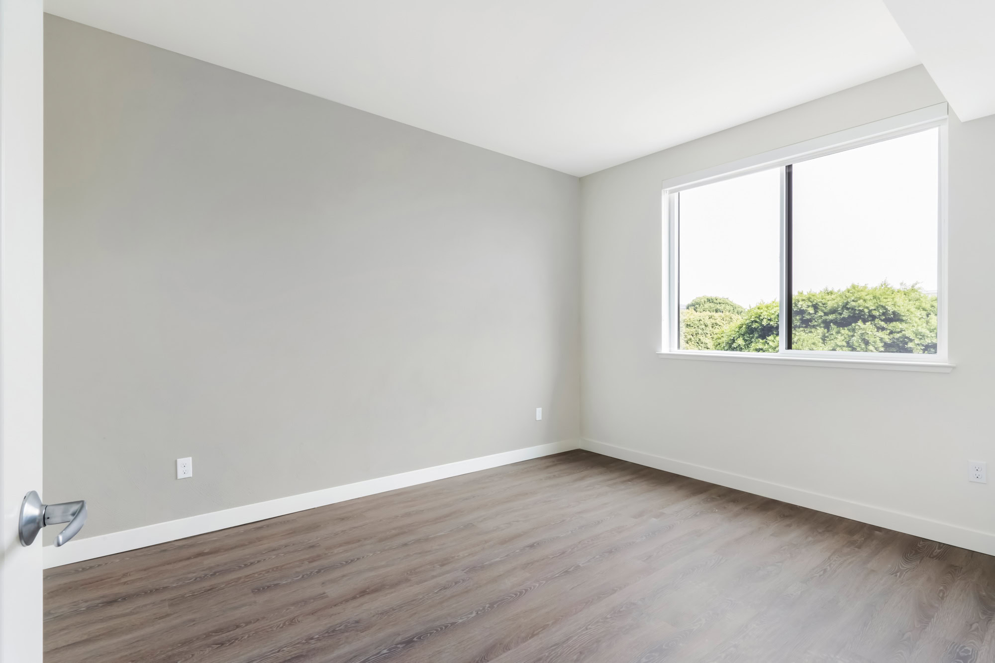 A bedroom with hardwood floors and windows at the Webster Eleven apartments in downtown Oakland