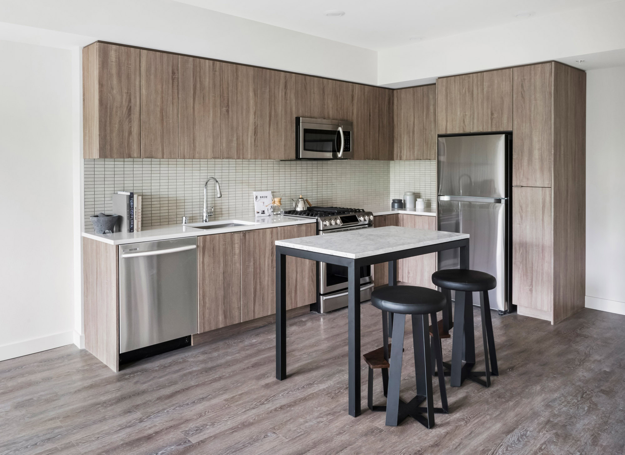 An open plan, L shaped kitchen with a kitchen island at the Webster Elevens downtown Oakland apartments for rent