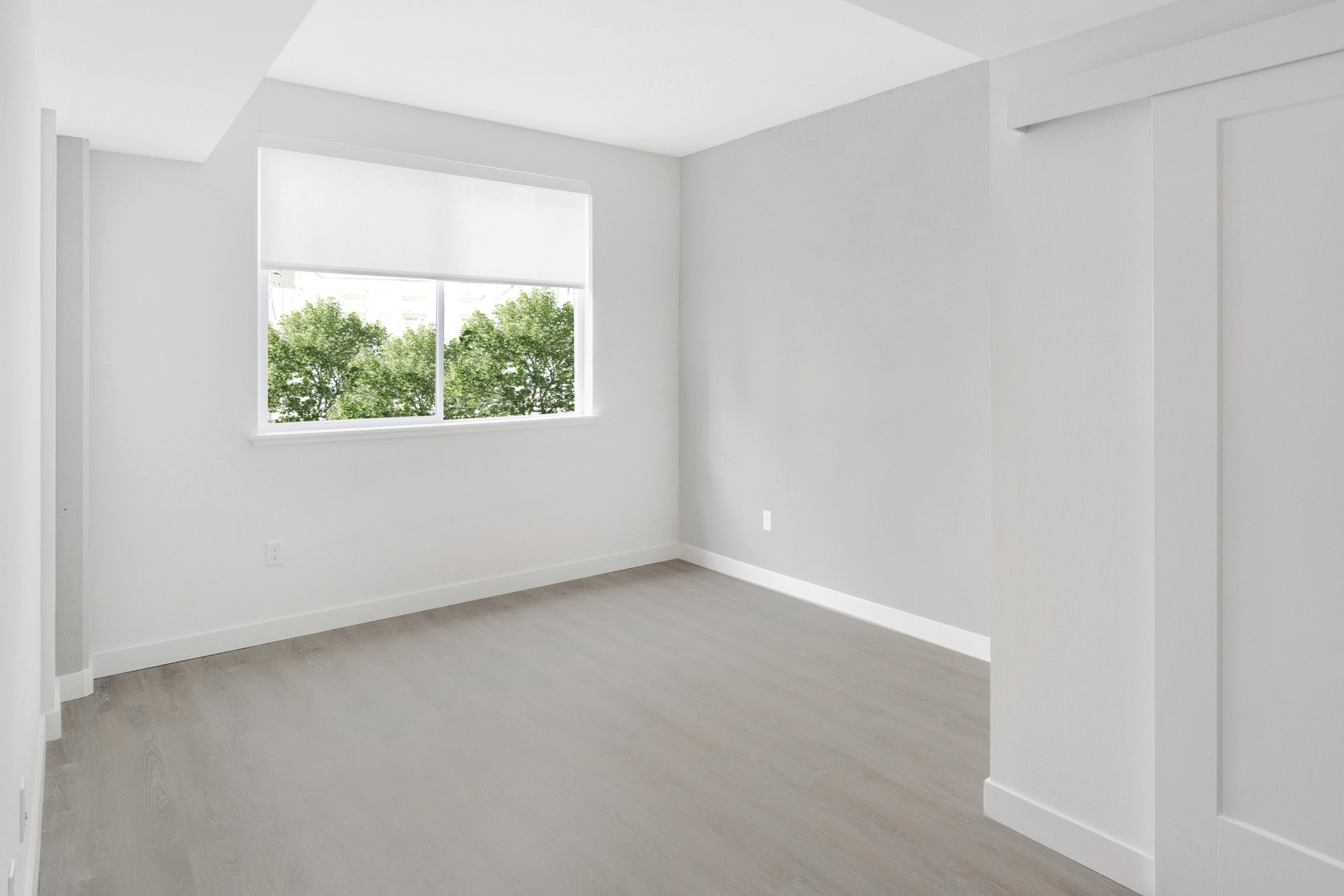 A living room with hardwood floors and a window at the Webster Eleven apartments in downtown Oakland