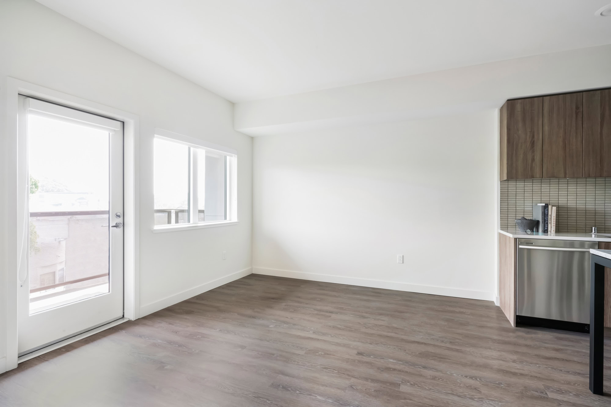An open plan living room with a door to the balcony at a Webster Eleven apartment in downtown Oakland