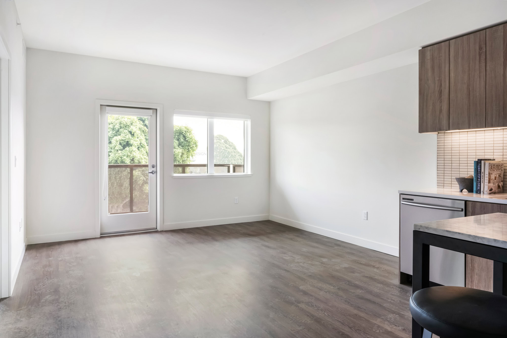 An open plan apartment living room with hardwood floors and a balcony door at the Webster Eleven apartments in downtown Oakland