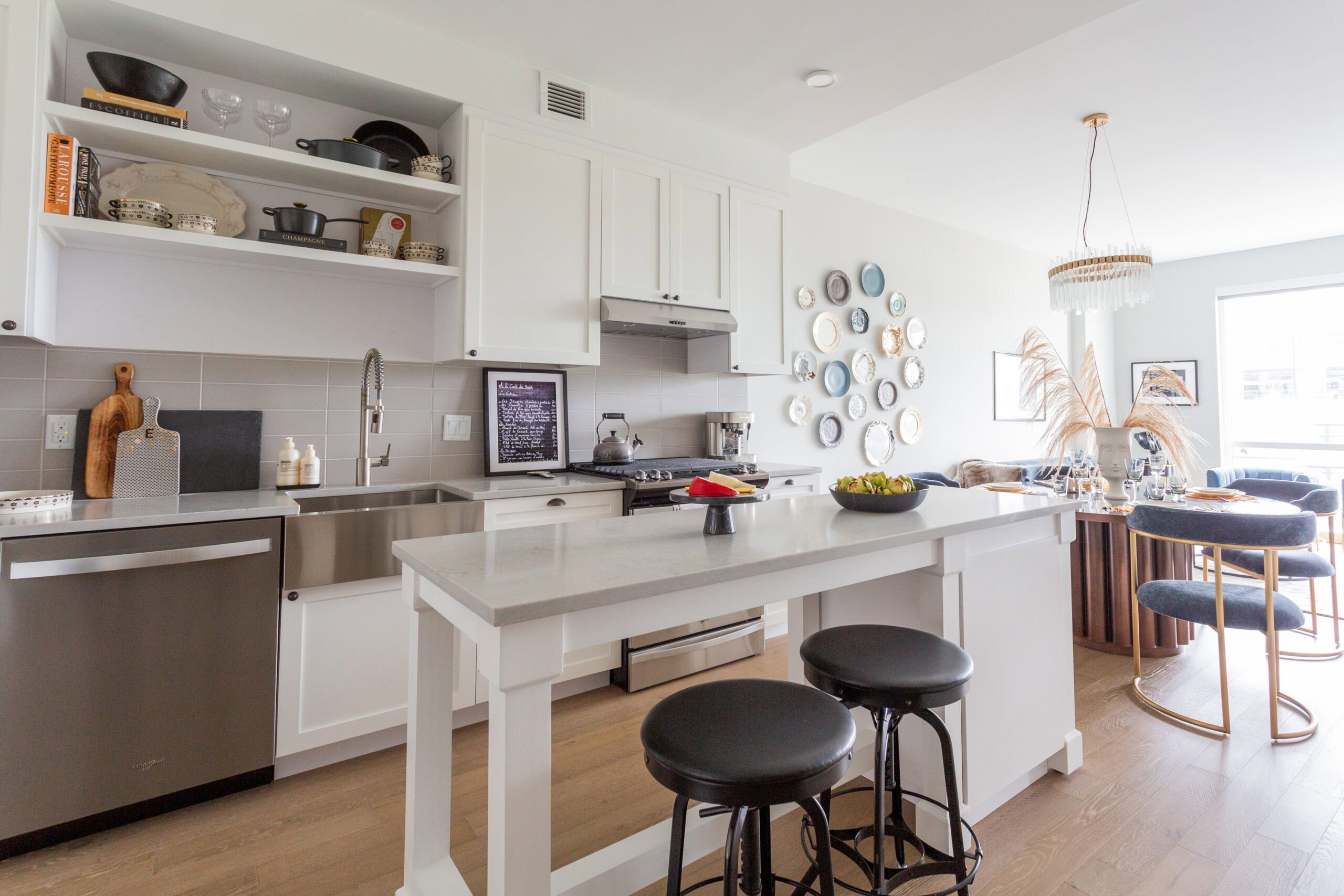 modern apartment kitchen with island, stainless steel appliances, white cabinets and gray tile backsplash
