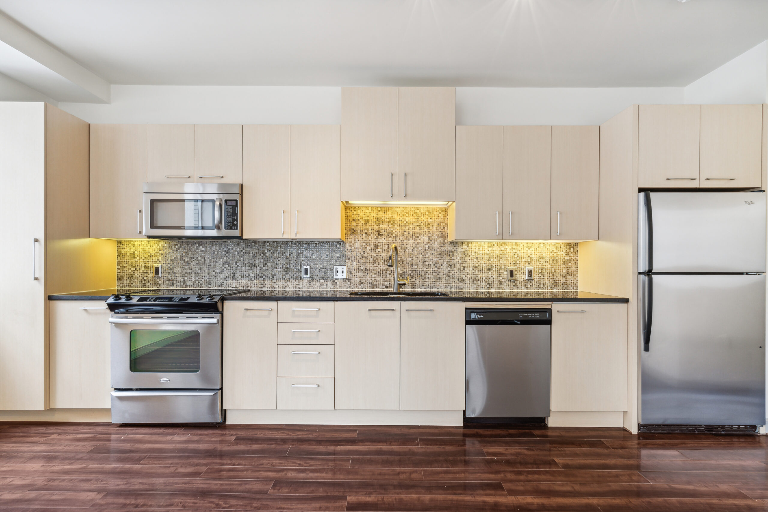 An open plan kitchen with hardwood floors and stainless steel appliances at The Continental apartments in Dallas TX