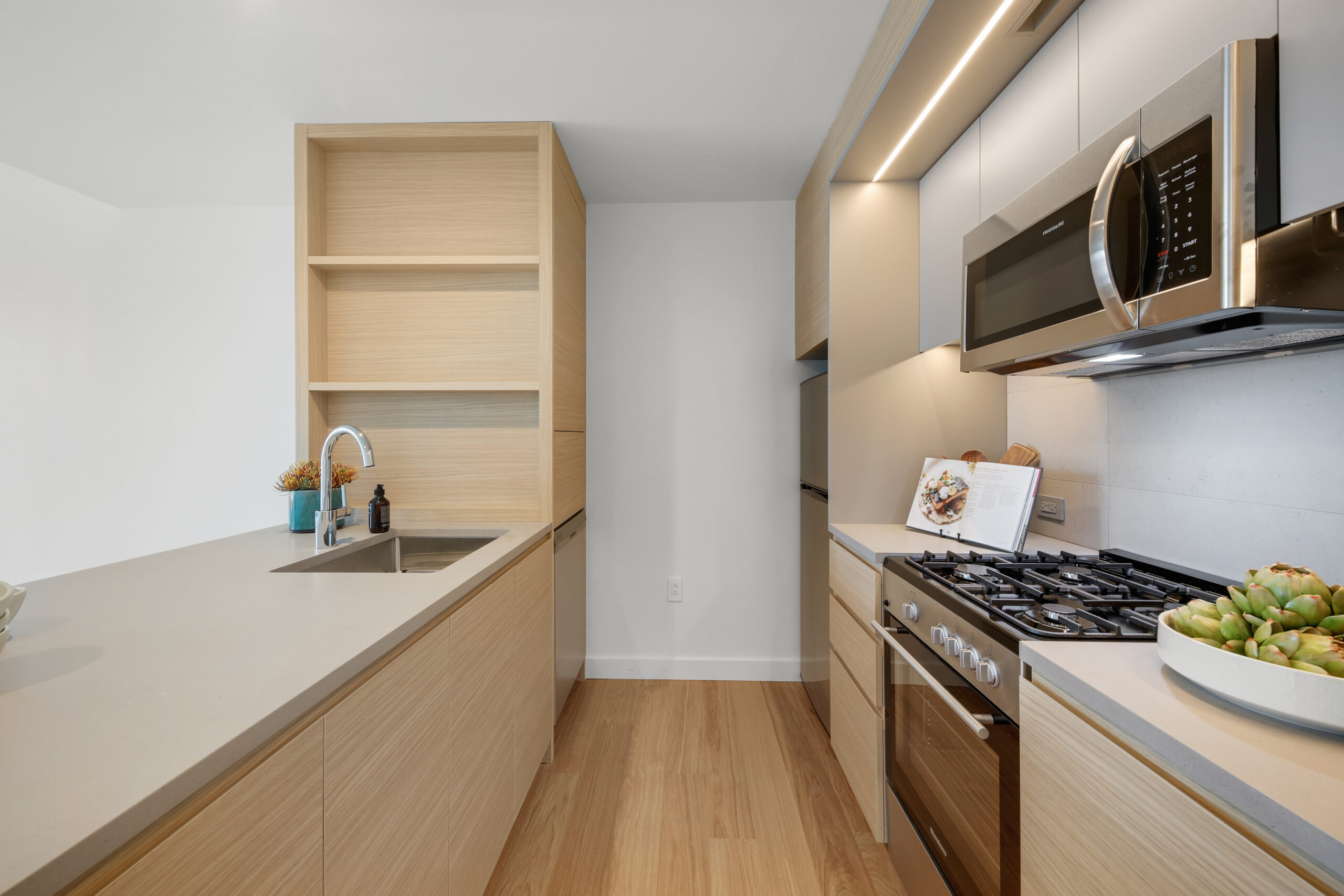 The kitchen with light natural cabinetry and countertops in an affordable housing apartment at Eagle+ West.