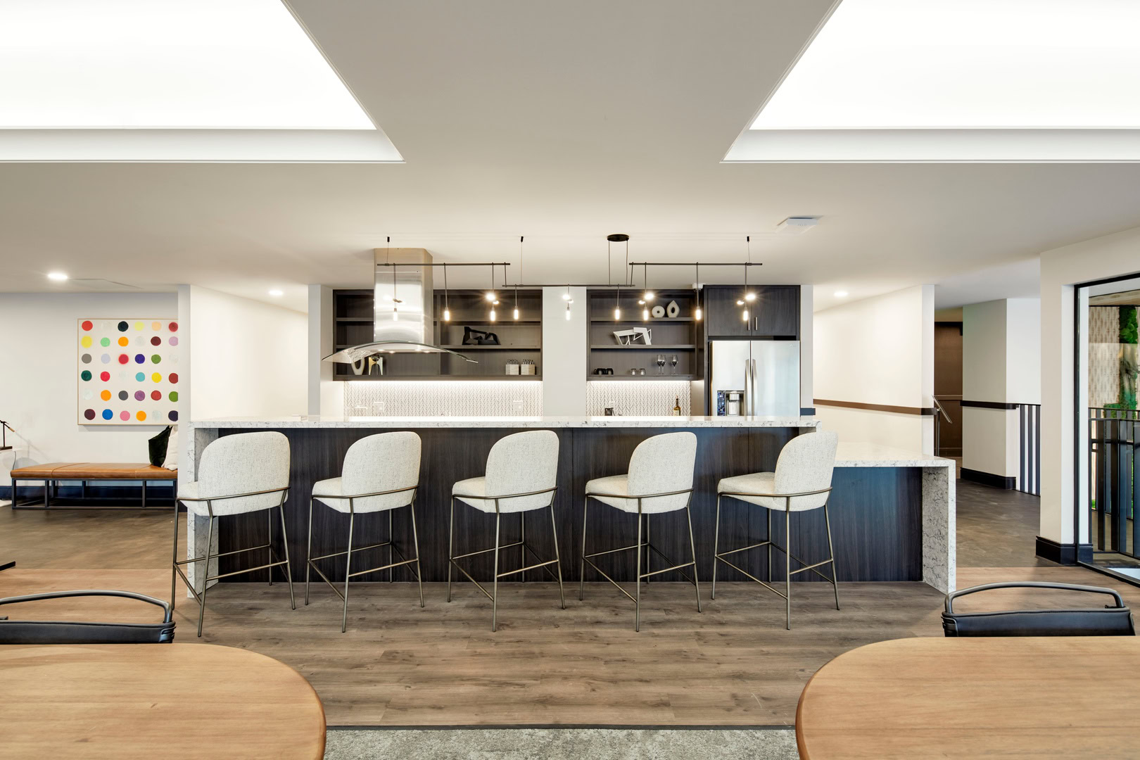 A kitchen area in a lounge space with high chairs in front of the large kitchen island at The logan luxury apartments in Oakland