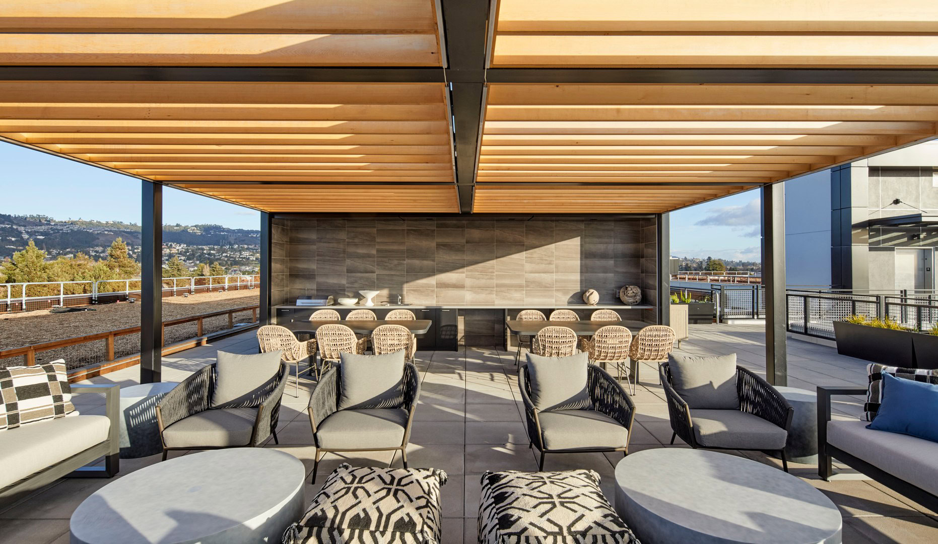 A rooftop lounge with 360 views, of the city skyline and dining tables in Oakland luxury apartments for rent at The Logan