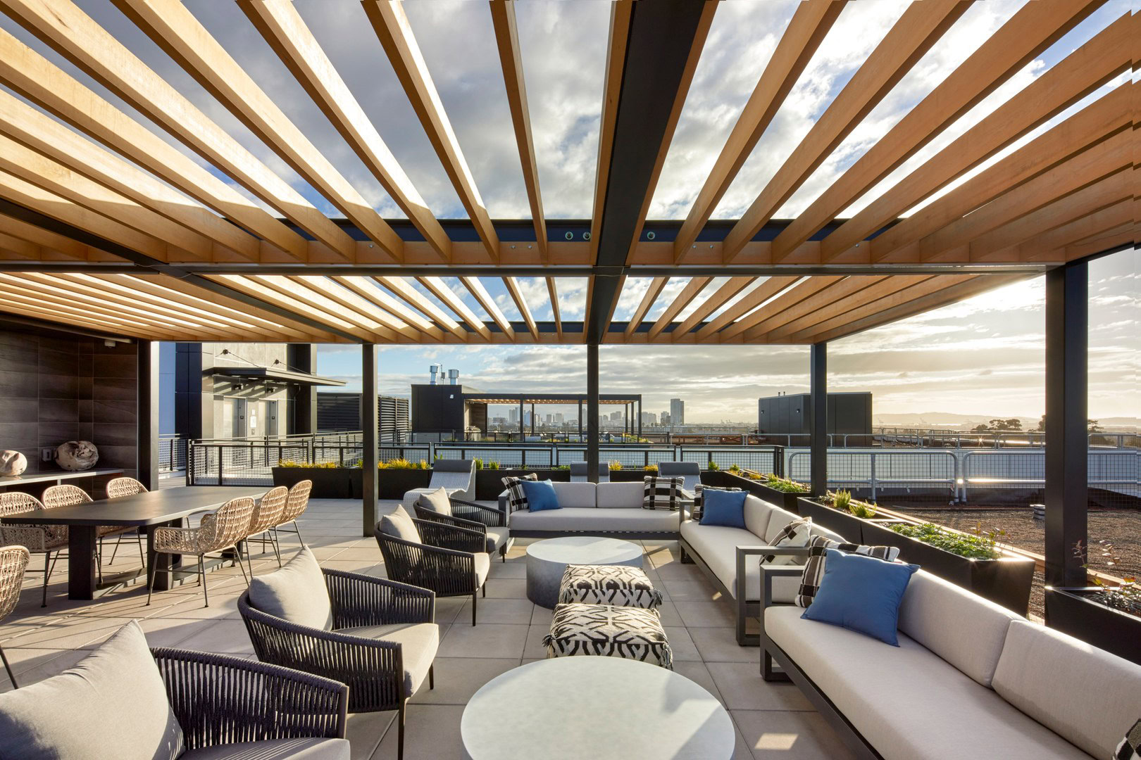 A rooftop lounge with 360 views, pergola shading of the city skyline and dining tables in Oakland luxury apartments for rent at The Logan