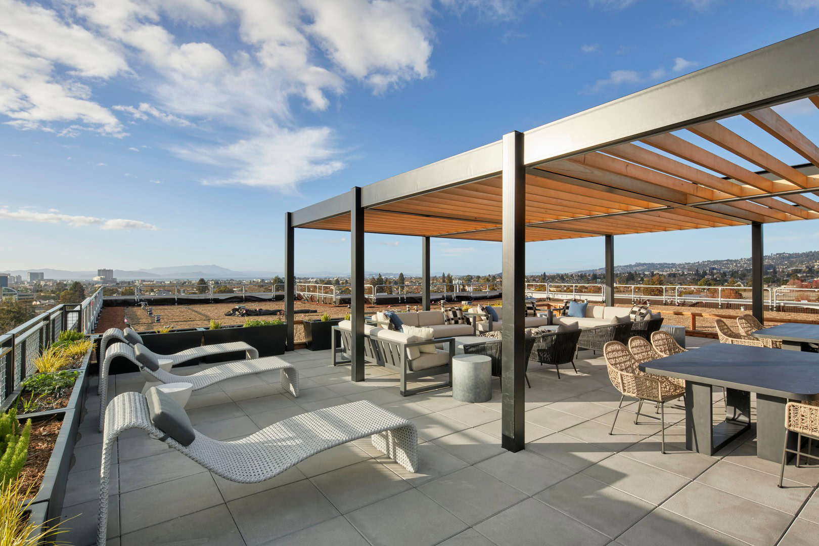 A rooftop lounge with 360 views, lounging chairs, and dining tables in Oakland luxury apartments for rent at The Logan