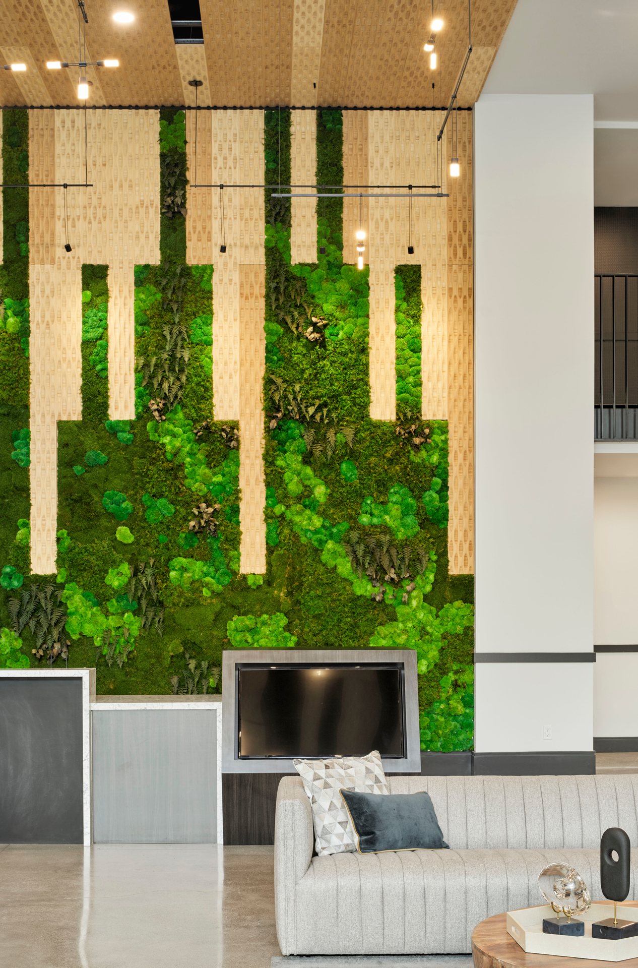 A lobby lounge and front desk with a textured green backdrop at The Logan luxury apartments in Temescal CA