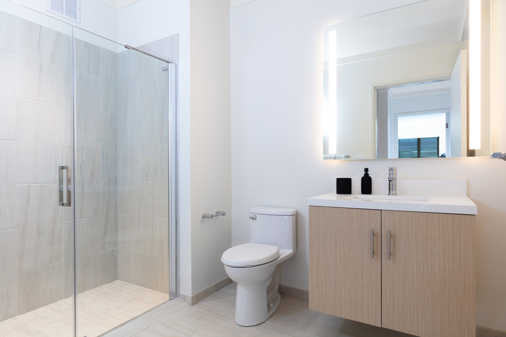 A bathroom with a spacious shower, and one sink vanity at the Logan apartments in oakland CA
