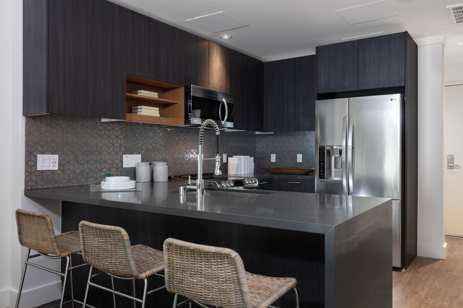 A peninsula kitchen with dining space and dark wood cabinets at The Logan temescal oakland ca apartments