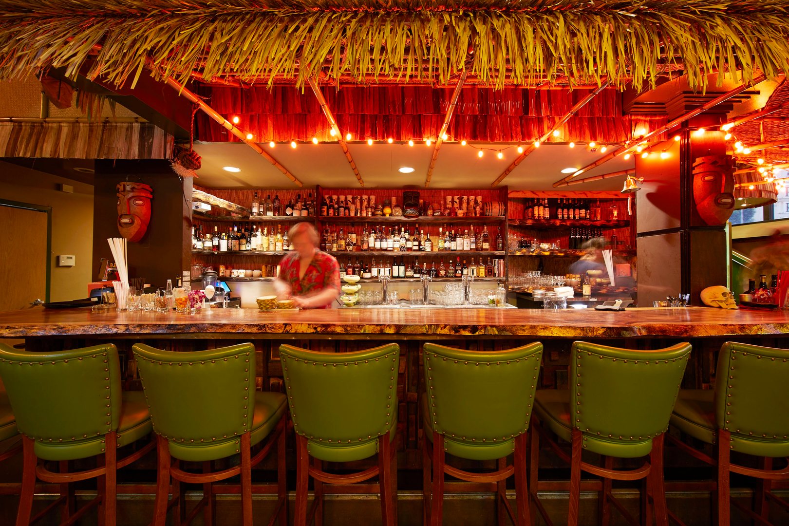 A bar with red fairy lights and hay roof for decor in a neighborhood near The Logan, a Temescal apartment