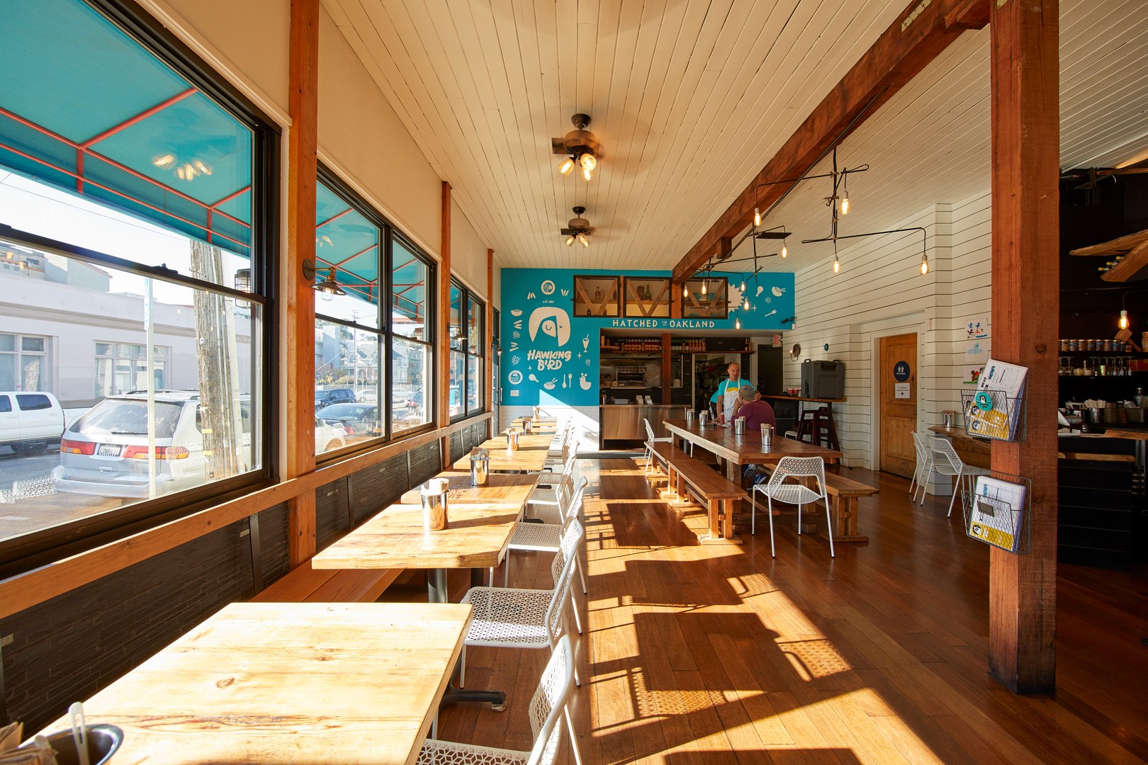 A restaurant with tables lined against a wall with windows bringing in natural lighting in a neighborhood near The Logan, Temescal apartments