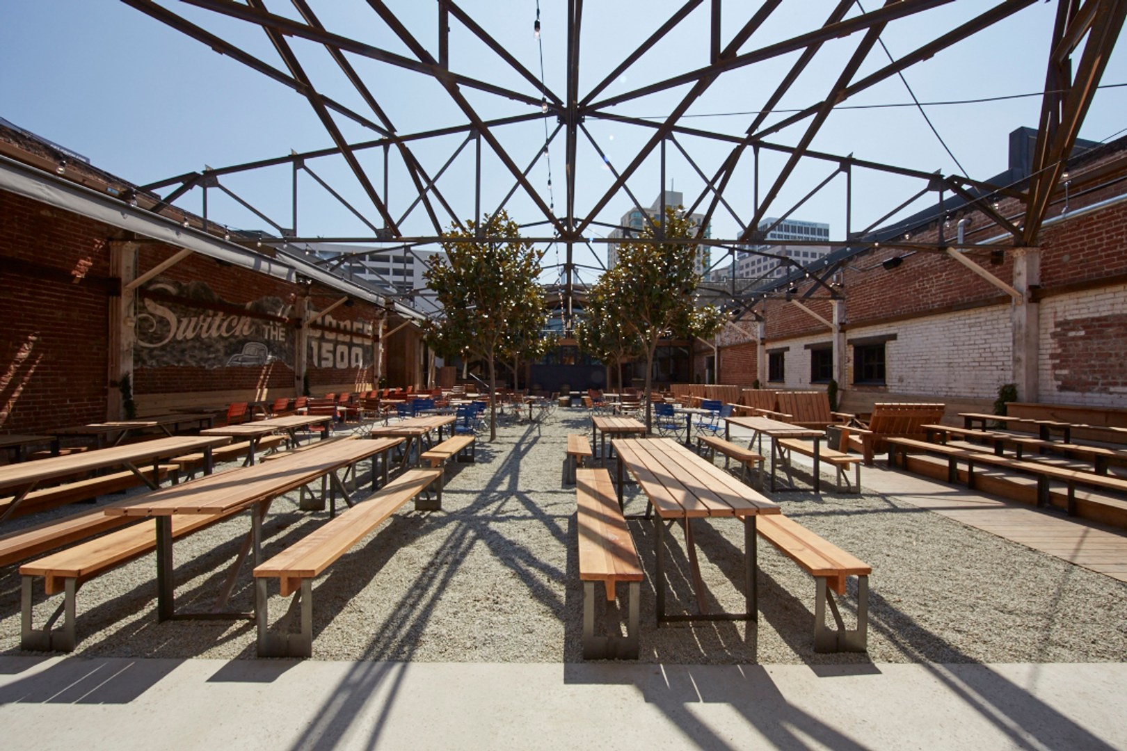A restaurant with several picnic tables outside with scaffolding over the yard in a neighborhood near The Logan, apartments in Temescal CA