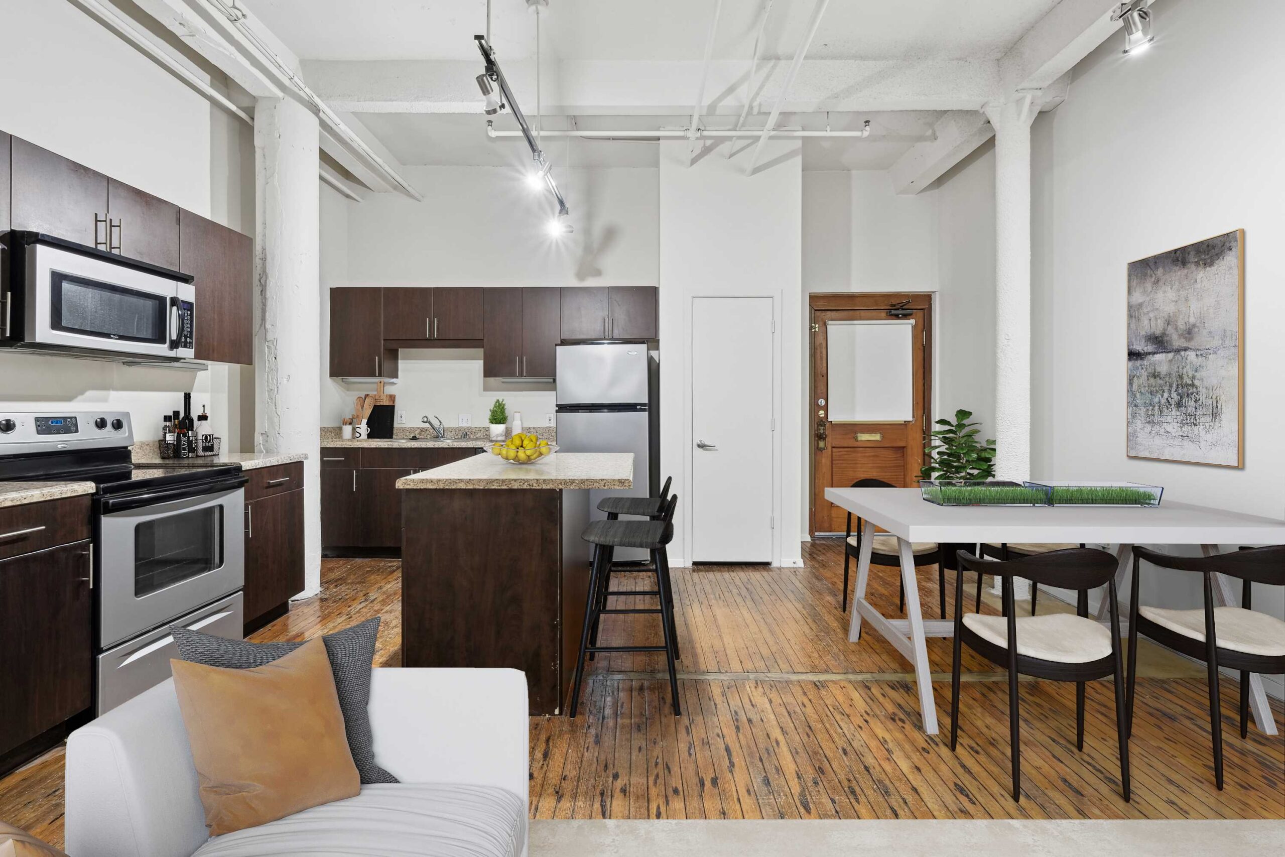 An open plan apartment with hardwood floors, a dining area and a kitchen with a kitchen island at The Wilson apartments in Dallas TX