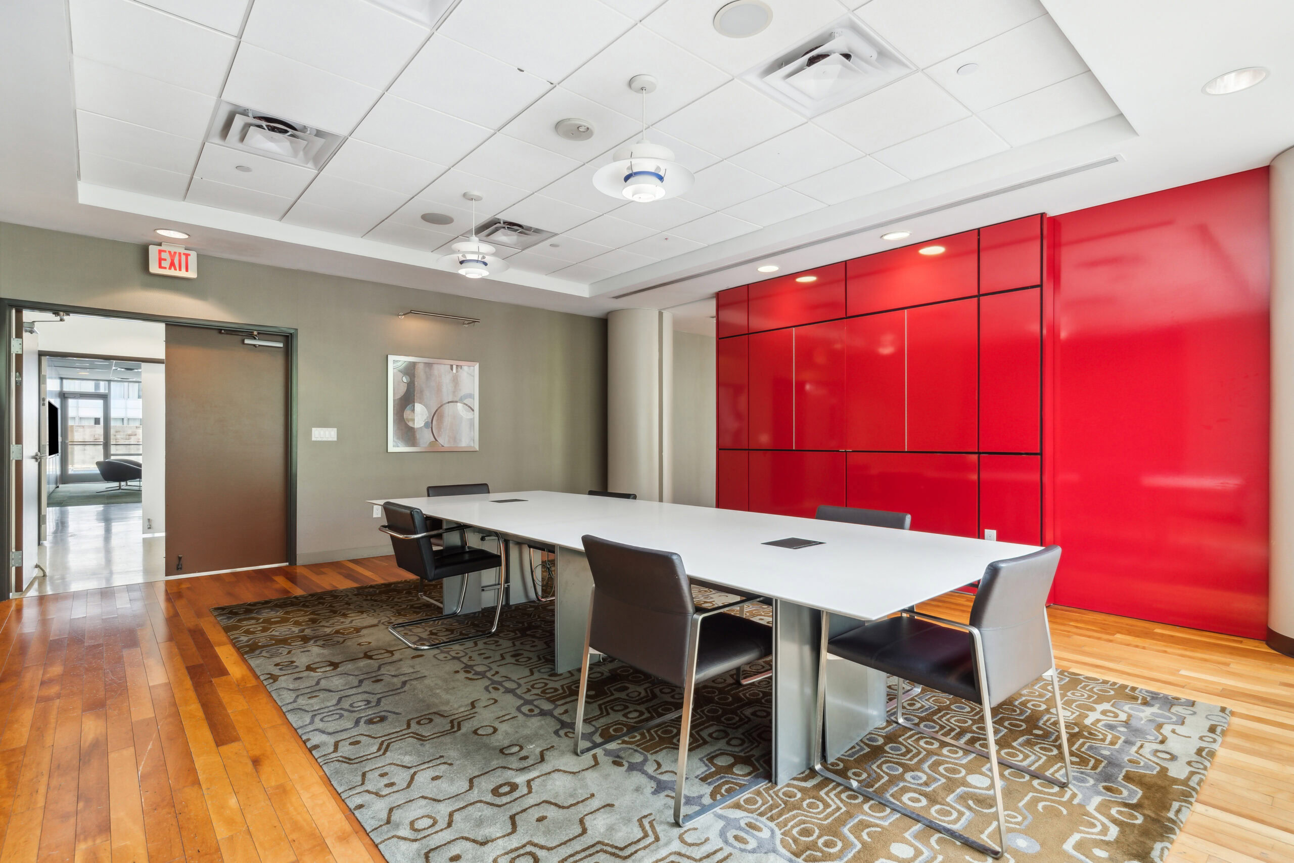 Modern, spacious conference room at The Continentals apartments with a large conference table and a red accent wall