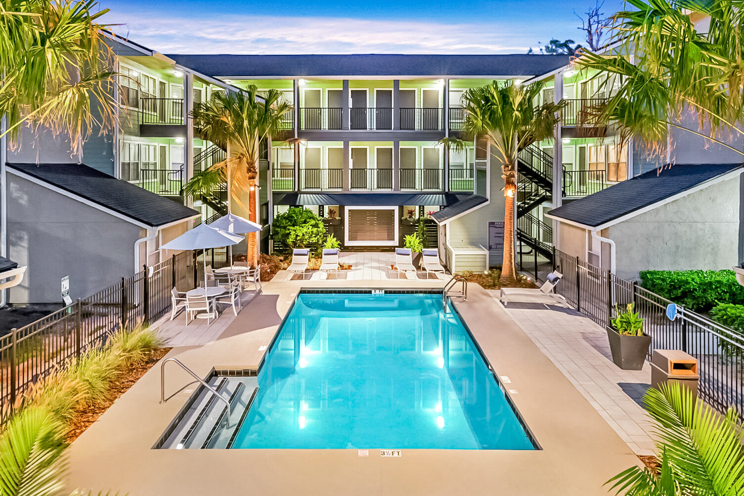Contemporary apartment community featuring a central swimming pool, lush landscaping, and outdoor seating areas, ideal for residents seeking comfort and leisure.