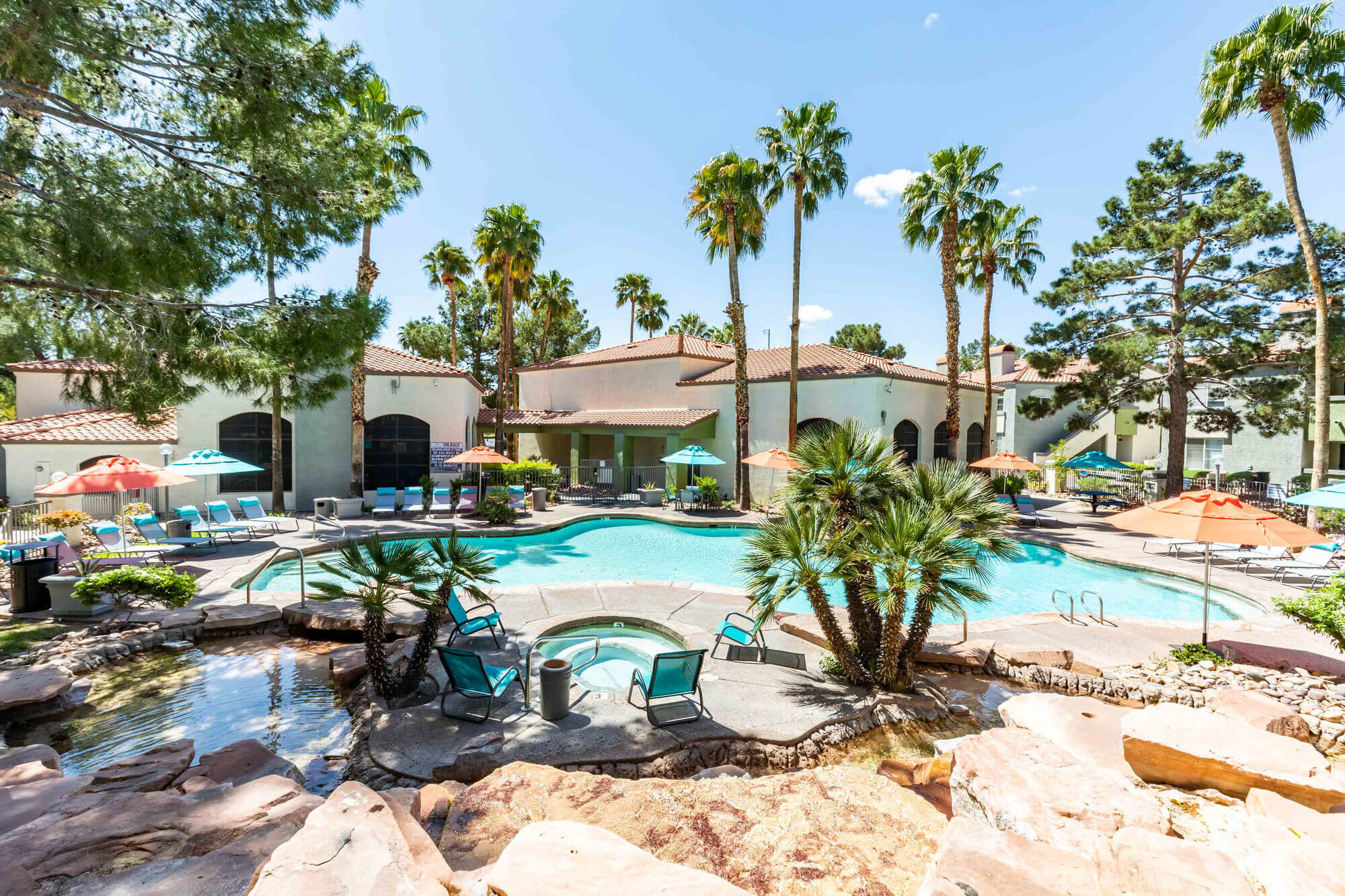 Luxurious outdoor pool area at Brookfield Properties featuring palm trees, lounge chairs, and shaded seating in a tropical setting.
