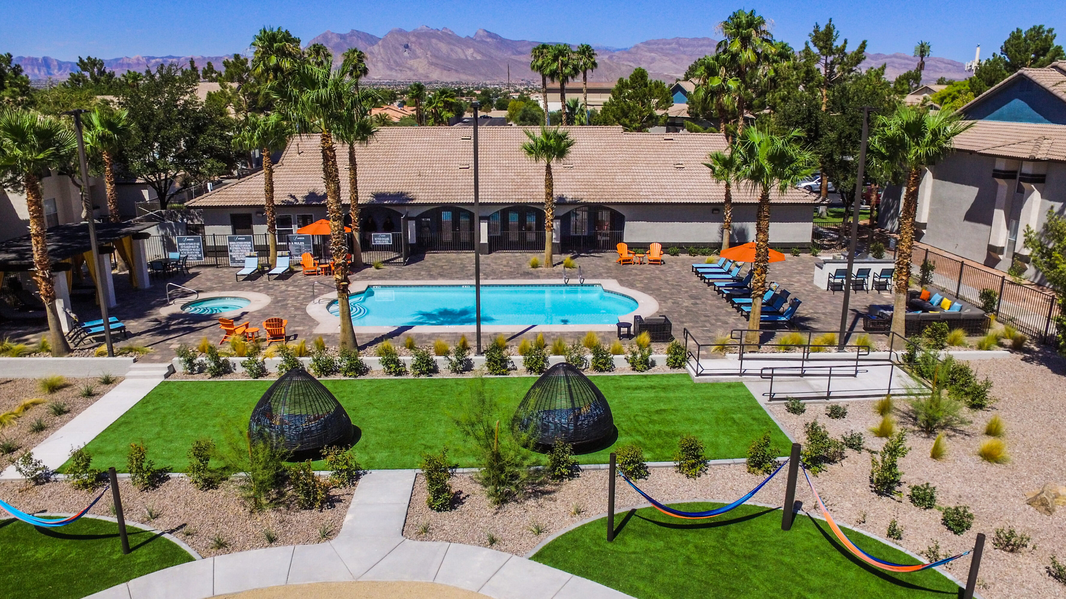 Poolside view at Brookfield Properties residential complex with palm trees and mountain backdrop.